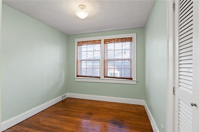 unfurnished room featuring dark hardwood / wood-style flooring and a textured ceiling