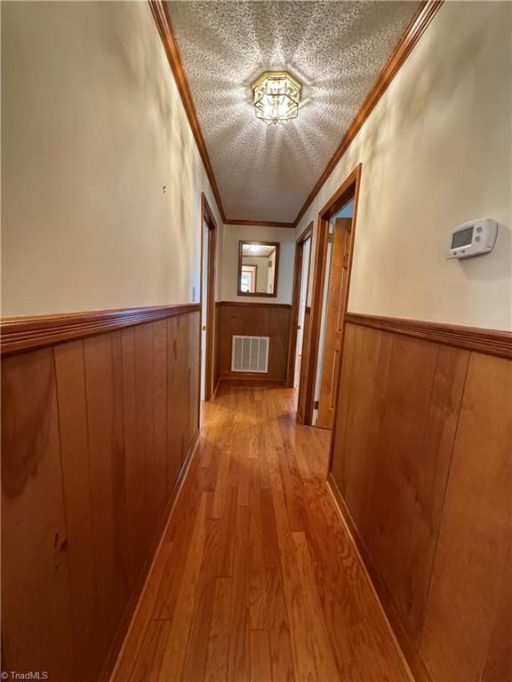 hallway with ornamental molding and light hardwood / wood-style flooring