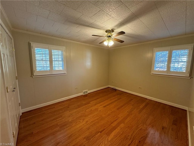 spare room with hardwood / wood-style floors, ornamental molding, and ceiling fan