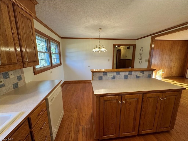 kitchen with tasteful backsplash, sink, hanging light fixtures, white dishwasher, and light hardwood / wood-style floors