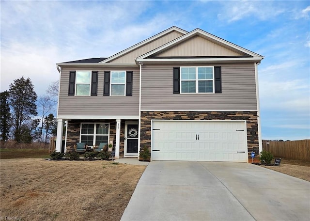 view of front of house with stone siding, covered porch, driveway, and fence