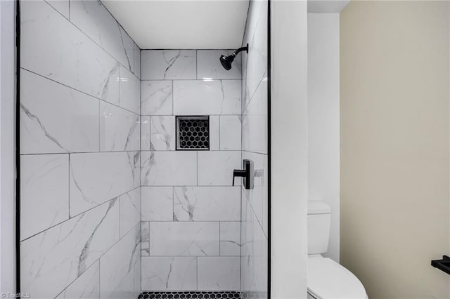 bathroom with a tile shower and toilet