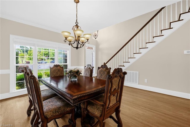 1905 Overshoot Ct, Greensboro, NC 27455 - dining area featuring a chandelier, light wood-style flooring, and stairs