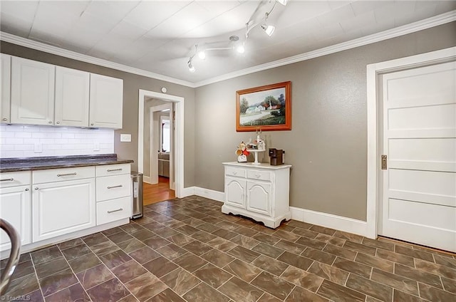 kitchen featuring tasteful backsplash, crown molding, white cabinets, and rail lighting