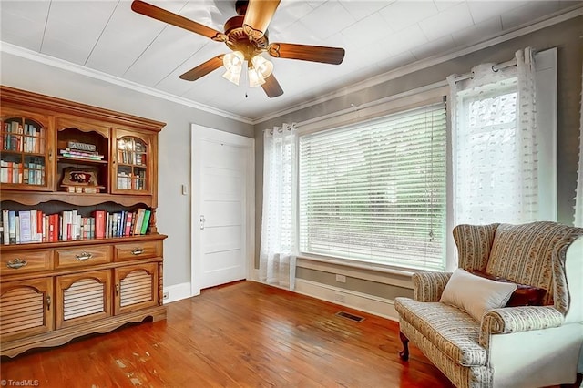 sitting room with hardwood / wood-style floors, ceiling fan, and crown molding