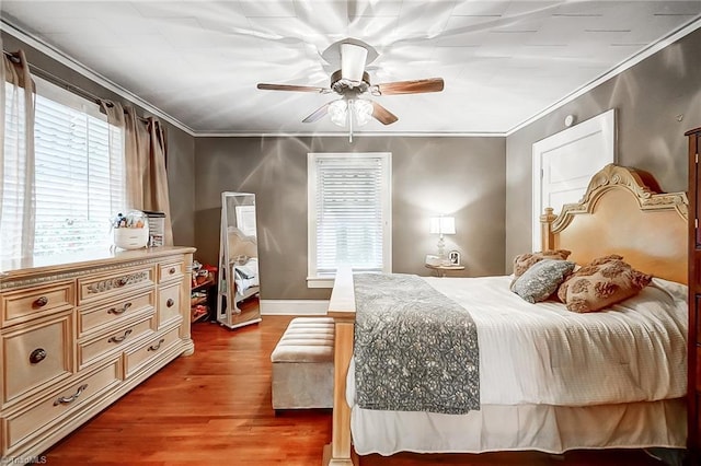 bedroom featuring hardwood / wood-style flooring, ceiling fan, crown molding, and multiple windows