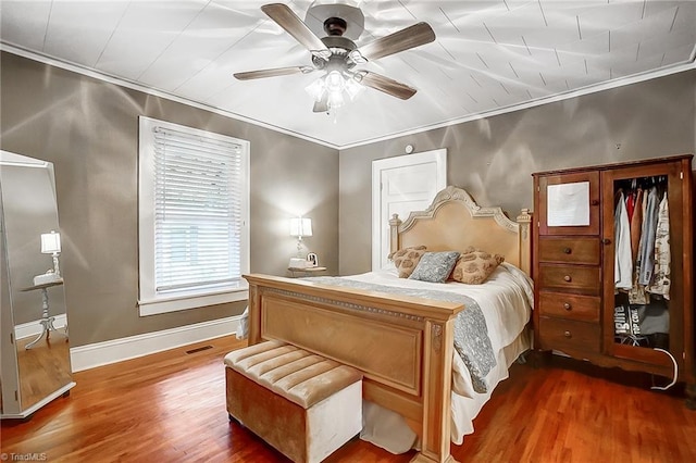 bedroom with dark hardwood / wood-style floors, ceiling fan, and ornamental molding