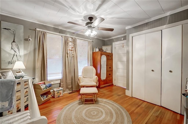 sitting room with light wood-type flooring, ceiling fan, and crown molding