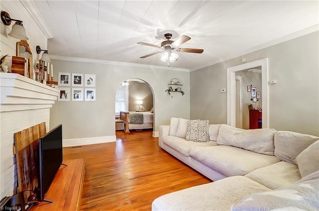 living room with a fireplace, hardwood / wood-style flooring, ceiling fan, and crown molding