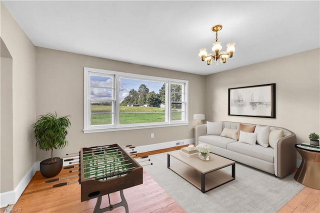 living room with baseboards, light wood-type flooring, and a notable chandelier