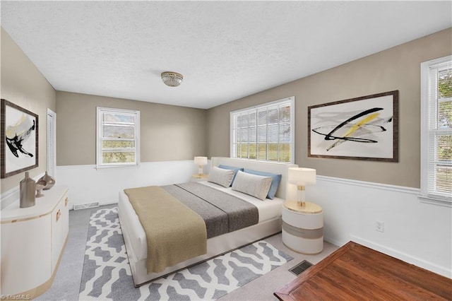 bedroom with light carpet, visible vents, and a textured ceiling