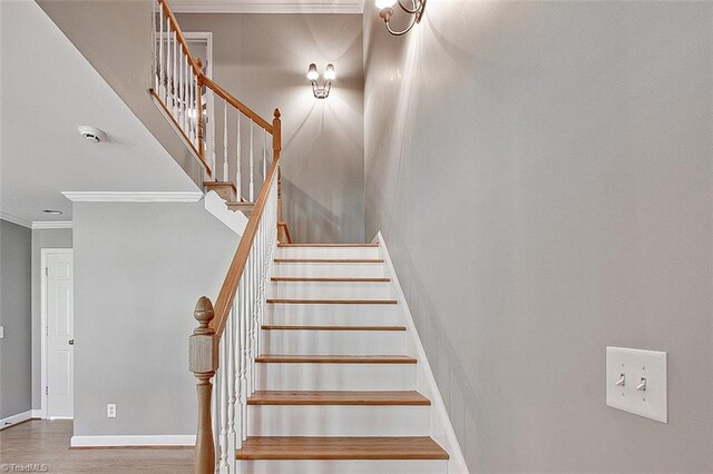 stairs featuring ornamental molding and hardwood / wood-style floors