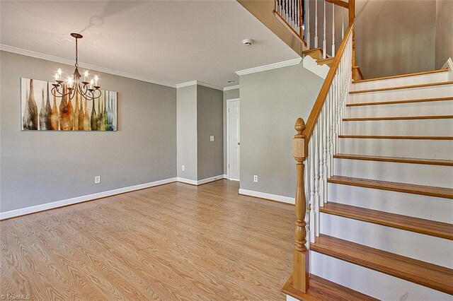 stairs featuring ornamental molding, a notable chandelier, and hardwood / wood-style flooring