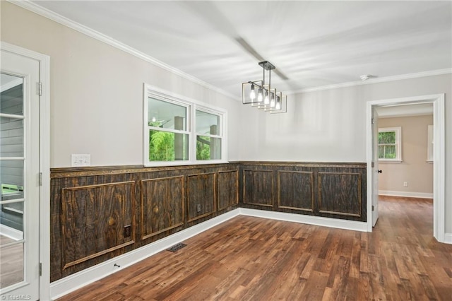 unfurnished dining area featuring healthy amount of natural light, wood finished floors, ornamental molding, and baseboards