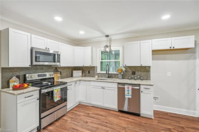 kitchen with appliances with stainless steel finishes, a sink, ornamental molding, decorative backsplash, and white cabinets