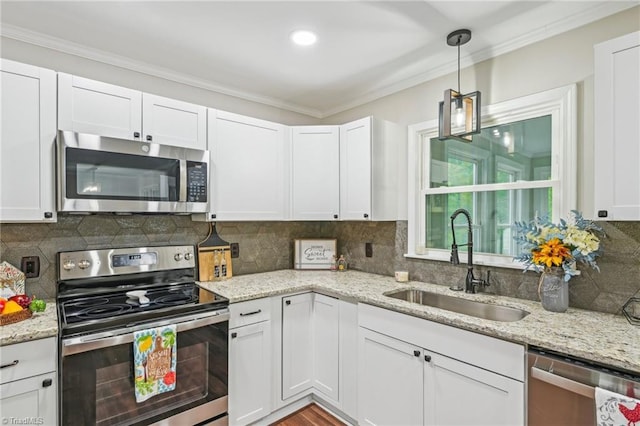 kitchen with appliances with stainless steel finishes, a sink, crown molding, white cabinetry, and light stone countertops