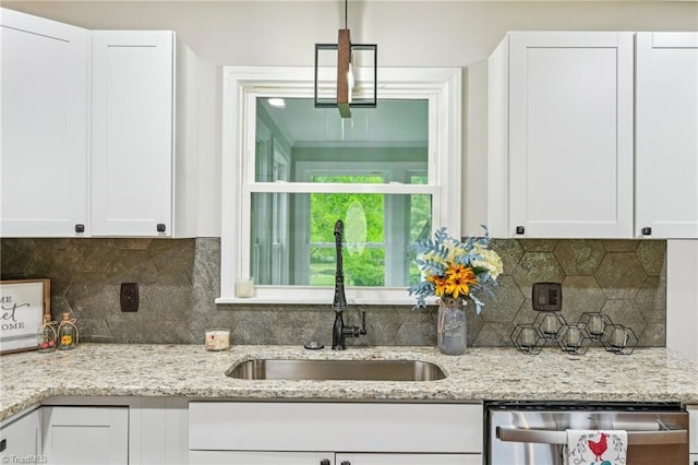 kitchen featuring a sink, stainless steel dishwasher, white cabinetry, light stone countertops, and decorative backsplash