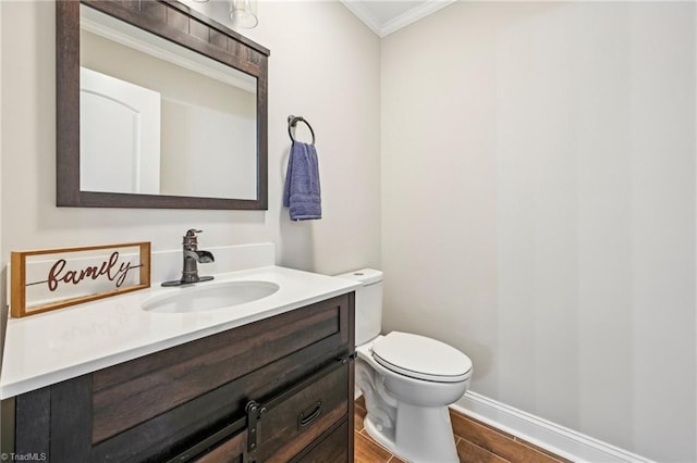 half bath featuring crown molding, vanity, toilet, wood finished floors, and baseboards