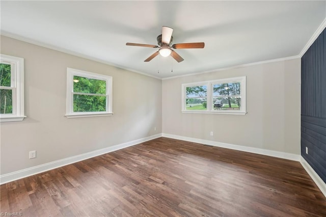 empty room with healthy amount of natural light, wood finished floors, baseboards, and crown molding