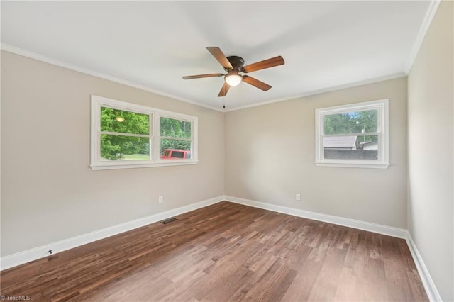 empty room featuring plenty of natural light, baseboards, crown molding, a ceiling fan, and wood finished floors