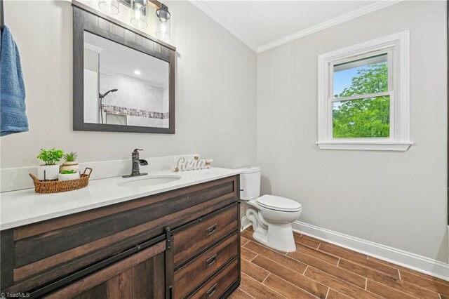 bathroom with crown molding, baseboards, vanity, toilet, and wood finished floors