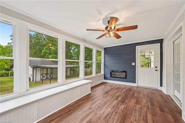 unfurnished sunroom with wood finished floors, crown molding, and baseboards