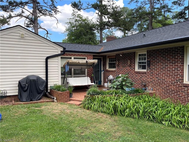 200 Trail Two, Burlington, NC 27215 - rear view of property featuring a deck, brick siding, a lawn, a chimney, and roof with shingles