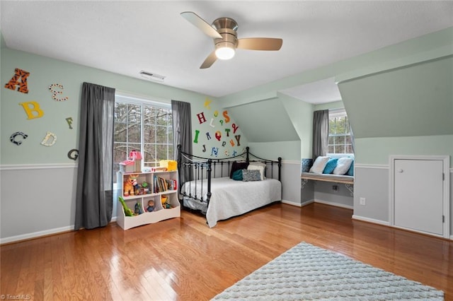 bedroom featuring wood finished floors, visible vents, baseboards, ceiling fan, and vaulted ceiling