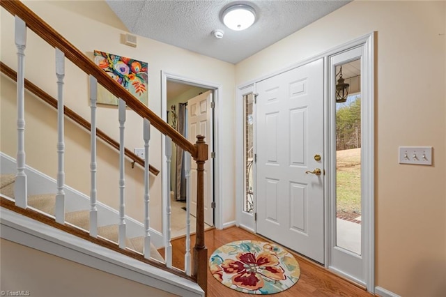 foyer featuring stairway, a textured ceiling, and wood finished floors