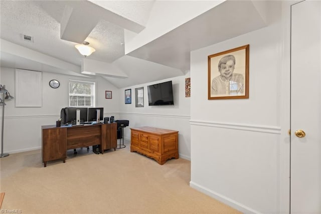 office area featuring visible vents, lofted ceiling, a textured ceiling, baseboards, and light colored carpet