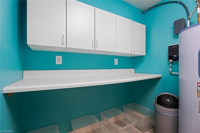 clothes washing area with a textured ceiling and electric water heater