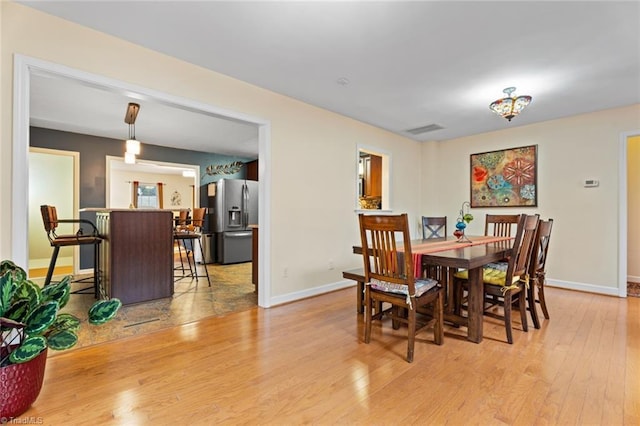 dining area with visible vents, light wood-style flooring, and baseboards