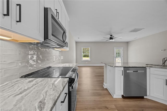 1337 Union Cross Rd, Kernersville, NC 27284 - kitchen with appliances with stainless steel finishes, a ceiling fan, wood finished floors, white cabinetry, and backsplash