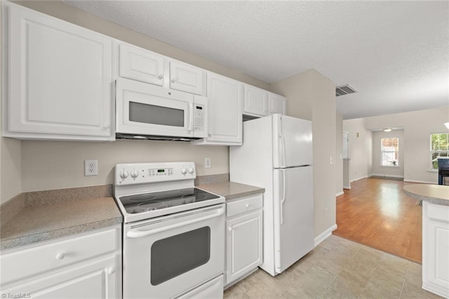 kitchen featuring white cabinets, light hardwood / wood-style flooring, a textured ceiling, and white appliances