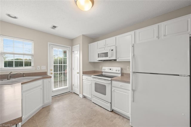 kitchen with sink, white cabinets, a textured ceiling, and white appliances