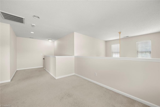 unfurnished room featuring light carpet and a textured ceiling