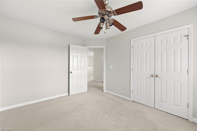 unfurnished bedroom featuring a closet, light colored carpet, and ceiling fan