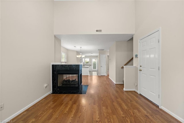 unfurnished living room with a notable chandelier, hardwood / wood-style flooring, and a multi sided fireplace