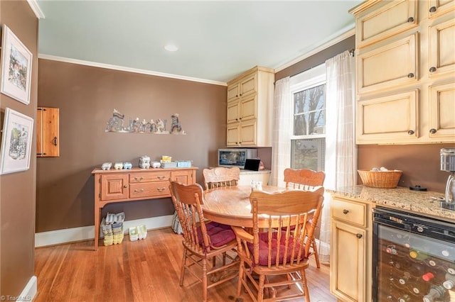 dining room featuring wine cooler, light hardwood / wood-style floors, and crown molding