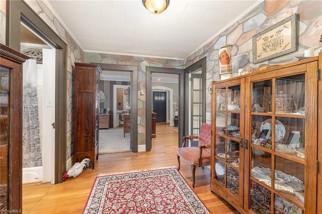 hallway with ornamental molding and light hardwood / wood-style floors