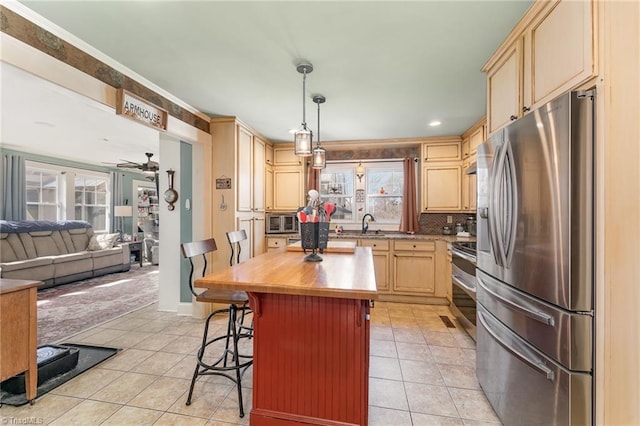 kitchen featuring a center island, a breakfast bar area, light tile patterned flooring, appliances with stainless steel finishes, and light brown cabinetry