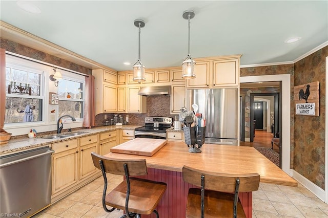 kitchen featuring hanging light fixtures, sink, ornamental molding, appliances with stainless steel finishes, and light tile patterned flooring