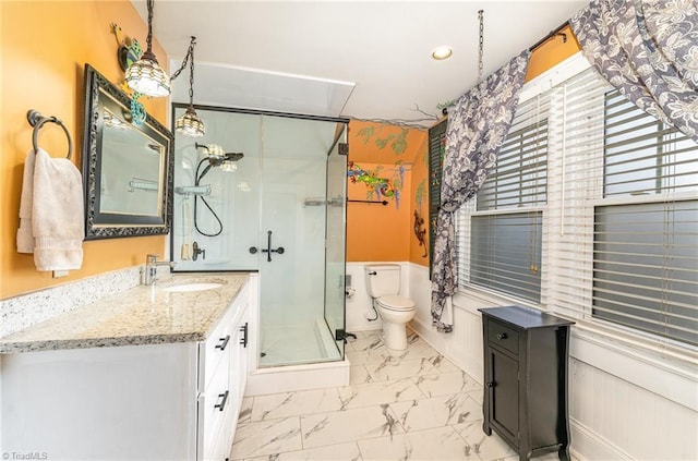 bathroom with toilet, vanity, and a shower with shower door