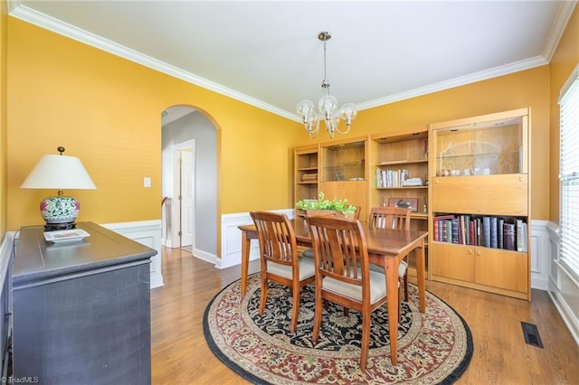 183 Scottsdale Dr, Advance, NC 27006 - dining space featuring arched walkways, ornamental molding, a chandelier, wood finished floors, and wainscoting