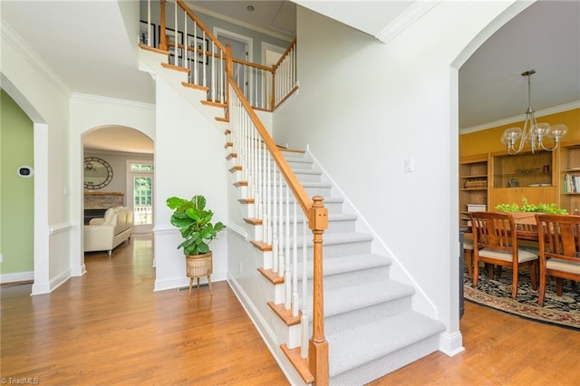 183 Scottsdale Dr, Advance, NC 27006 - stairs featuring wood finished floors, arched walkways, crown molding, a chandelier, and baseboards