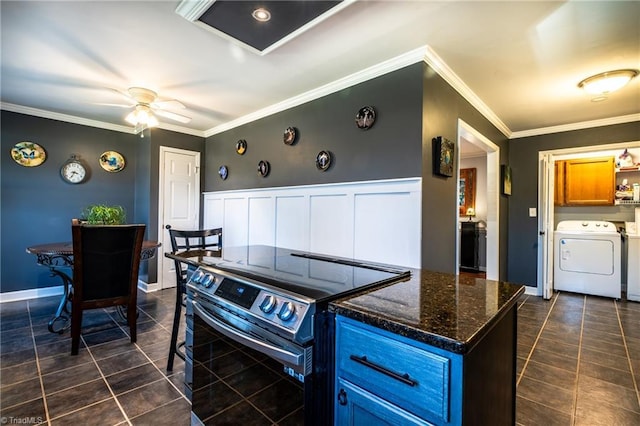 kitchen featuring washer / dryer, electric range, ornamental molding, dark tile patterned flooring, and dark stone counters