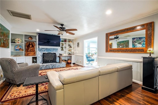 living room with crown molding, a fireplace, dark hardwood / wood-style flooring, and built in shelves