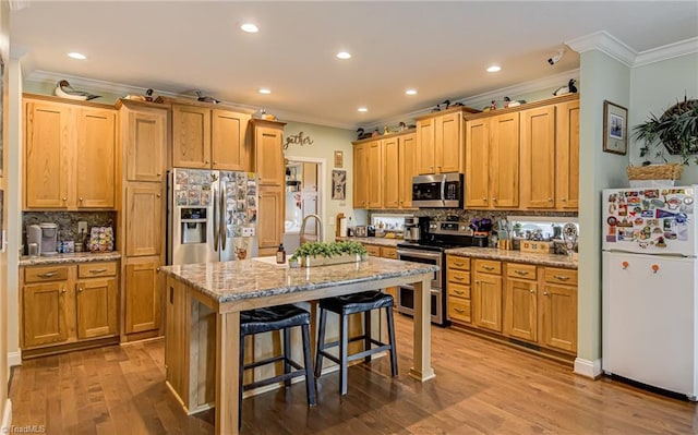 kitchen featuring light stone counters, crown molding, stainless steel appliances, wood finished floors, and a kitchen breakfast bar