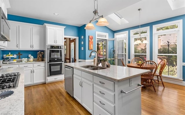 4802 Worchester Pl, Jamestown, NC 27282 - kitchen featuring a sink, a skylight, appliances with stainless steel finishes, light wood-style flooring, and white cabinetry