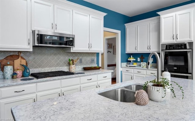 4802 Worchester Pl, Jamestown, NC 27282 - kitchen featuring stainless steel appliances, white cabinets, light stone counters, decorative backsplash, and a sink